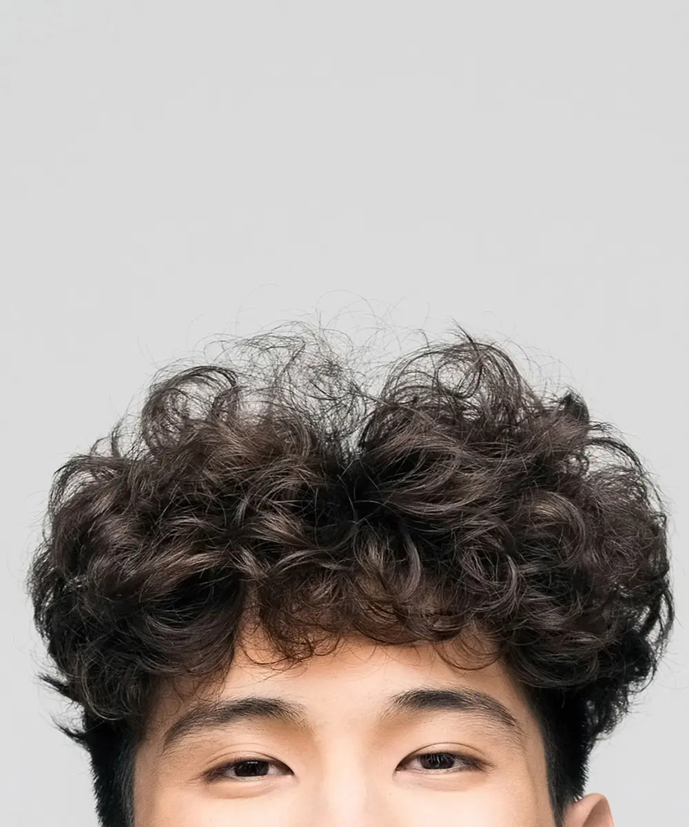 Oberkopf und Augen-Ausschnitt eines jungen Mannes mit dunklem lockigen Haar asiatischer Herkunft