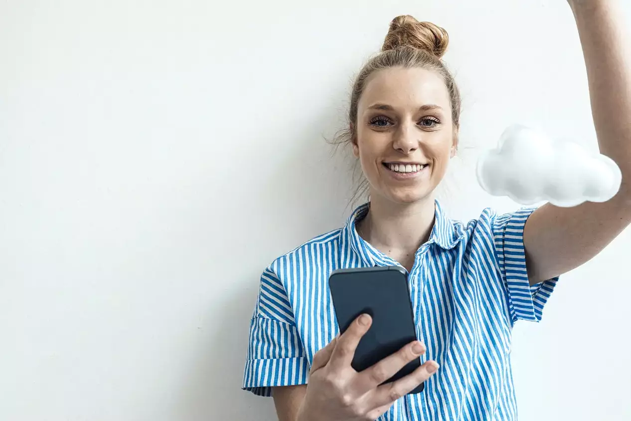 Eine lächelnde junge Frau, die ein Handy in der Hand hält